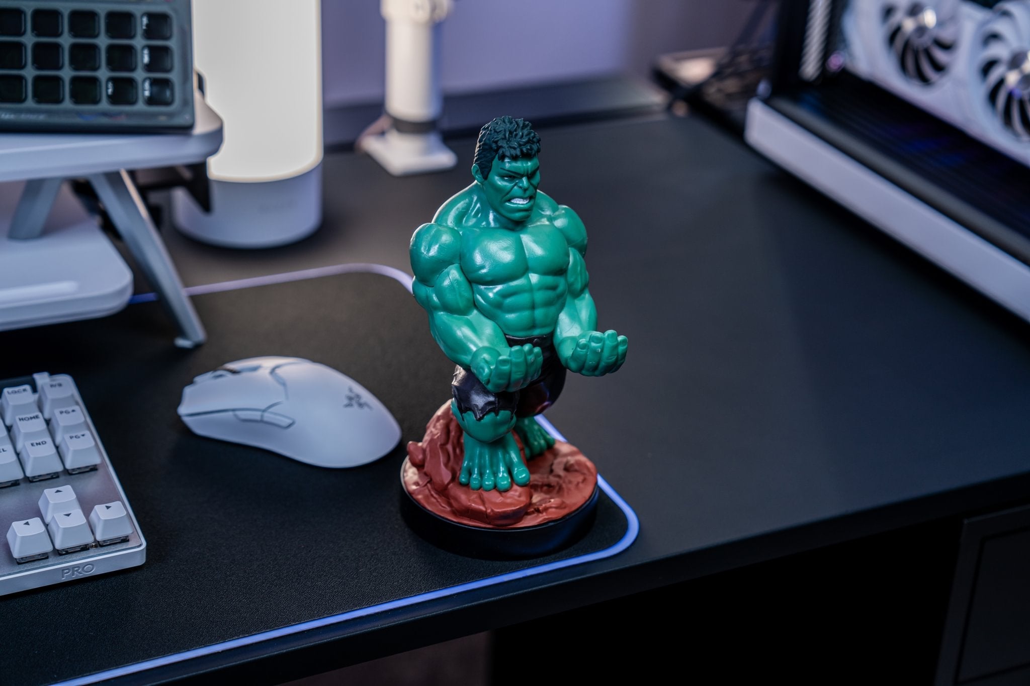 Hulk Cable Guy controller holder displayed on a gaming desk beside a keyboard, mouse, and RGB-lit PC setup.