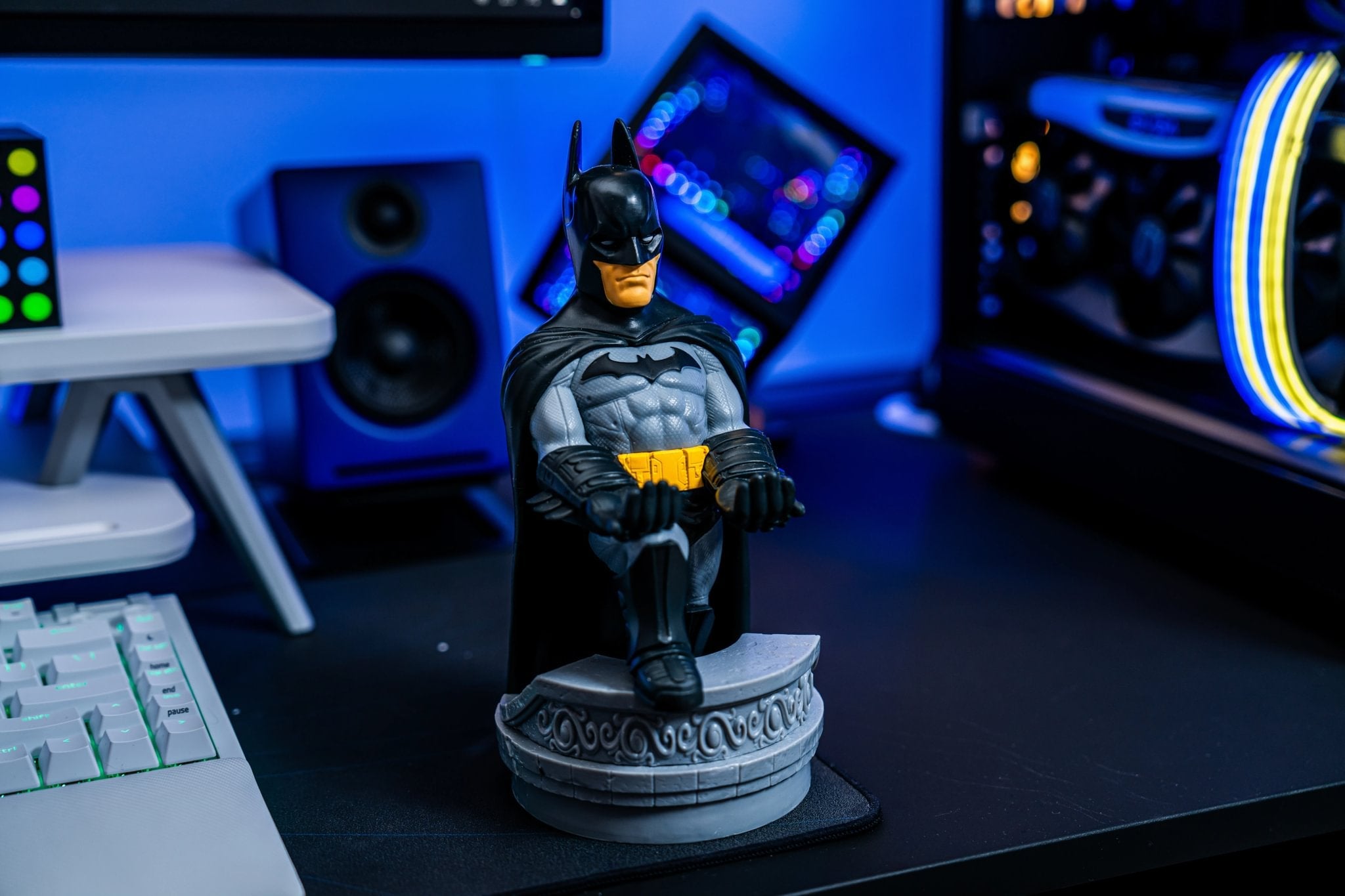 Batman Cable Guy figure displayed on a gaming desk setup with RGB lighting and computer equipment in the background.