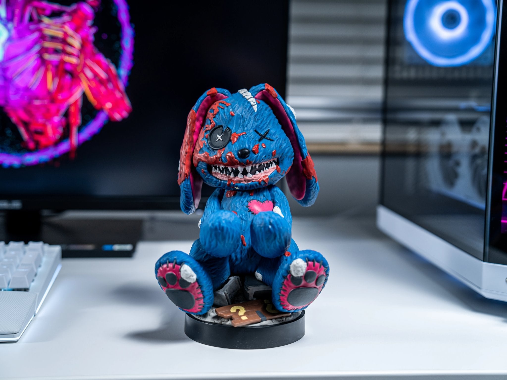 Mister Peeks Cable Guy collectible figure displayed on a white gaming desk with illuminated monitors in the background.