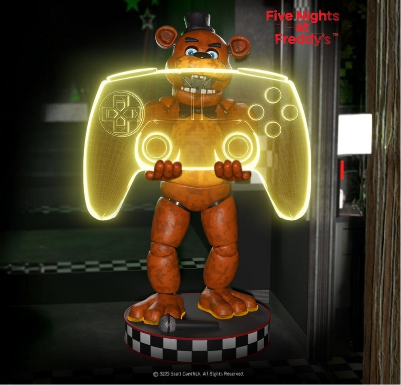 Freddy Fazbear from Five Nights at Freddy’s standing on a circular stage base holding a glowing yellow holographic game controller. The Five Nights at Freddy’s logo is visible in the top right corner, and a microphone lies on the base near Freddy’s feet.